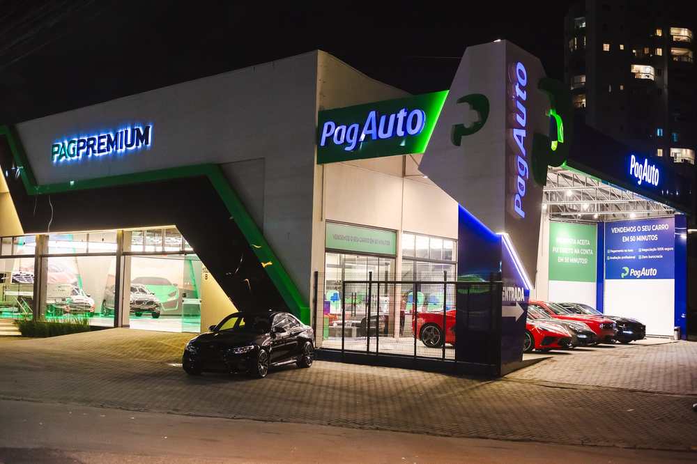 Fachada da PagAuto à noite com letras caixa iluminadas e painéis em ACM verde e azul